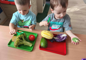 Dzieci oglądają przez lupę warzywa i dokładnie dotykają ich powierzchni.