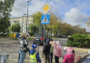 Nauczycielka pokazuje dzieciom znak drogowy.