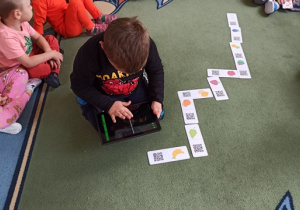 dzieci grają w domino z wykorzystaniem tabletu