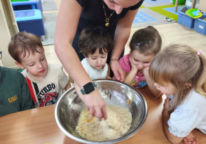 Dziewczynka z pomocą nauczyciela miesza masę na gofry.