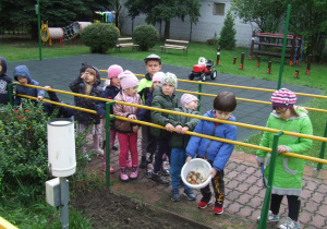 dzieci w ogrodzie stoją przed przygotowaną grządką