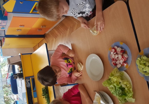 Dzieci smarują kanapki masłem.