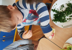 Dzieci dekorują kanapki warzywami.
