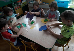 Dzieci przewlekają sznurówki przez dziurki