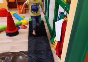 Chłopiec ćwiczy na ścieżce sensorycznej.