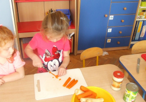 Dziewczynka kroi marchewkę.