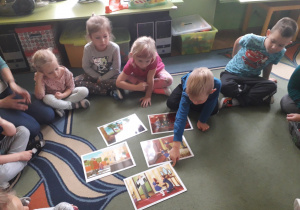dzieci siedzą na dywanie, chłopiec wskazuje na obrazek