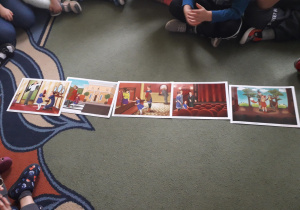 dzieci siedzą na dywanie a przed nimi leży ułożona historyjka obrazkowa