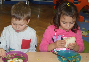 Dzieci jedzą kolorowe kanapki.