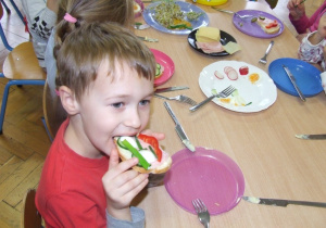 Chłopiec je kolorową kanapkę.