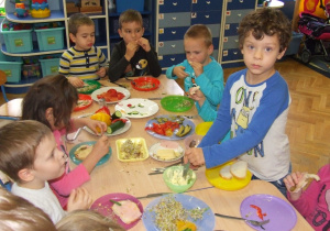 Dzieci jedzą kolorowe kanapki.