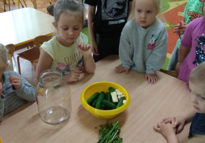 Dzieci wkładają ogórki do słoika.