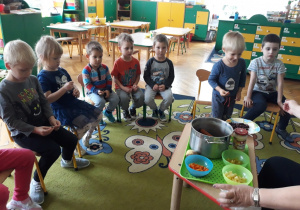 Dzieci oglądają i smakują składniki sałatki.