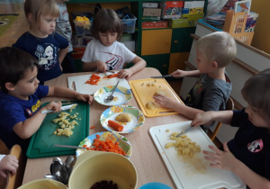 Dzieci kroją ugotowaną marchewkę i ziemniaki.