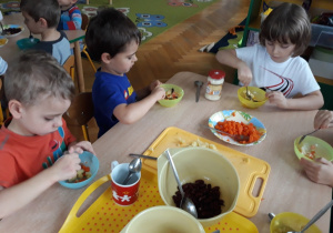 Dzieci jedzą sałatkę warzywną.