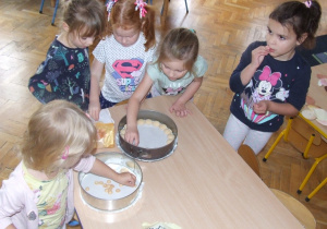 Dziewczynki wkładają biszkopty do tortownicy.