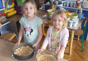 Dziewczynki wkładają biszkopty do tortownicy.