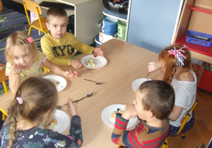 Dzieci jedzą zrobiony przez siebie torcik.