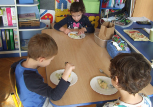 Dzieci jedzą zrobiony przez siebie torcik.