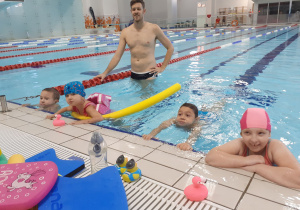Dzieci ćwiczą w basenie pod kierunkiem instruktora