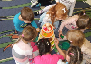 Dzieci układają produkty na drewnianej piramidzie.