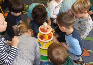 Dzieci układają produkty na drewnianej piramidzie.
