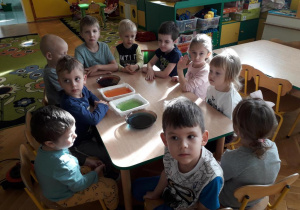 Dzieci siedzą przy stole, na stole są kolorowe galaretki.
