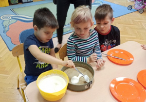 Dzieci wykładają masę śmietanową do tortownicy