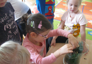 Dzieci wkłądają gałązki do wazonu.
