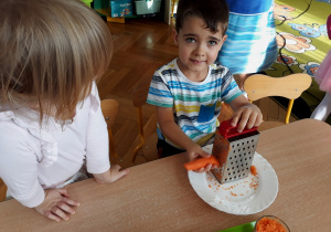 Dzieci ucierają marchewkę na tarce