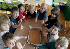 Dzieci pokazują zrobione ciasto marchewkowe.