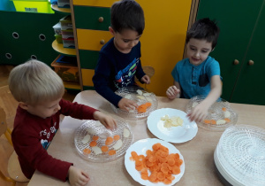 Dzieci układają plastry jabłek i marchewki na tacki suszarki