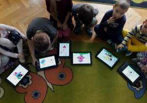 Dzieci pokazują misie narysowane na tabletach