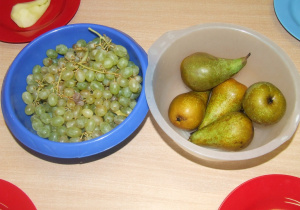 Gruszki i winogrona w miskach.