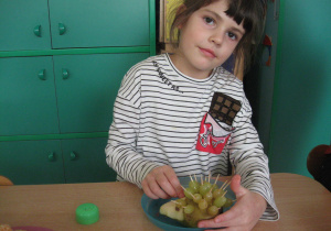 Dziewczynka wkłada wykałaczkę w gruszkę.