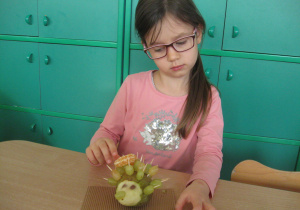 Dziewczynka wkłada mandarynkę na wykałaczkę