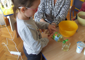dziewczynka nalewa olej do szklanki