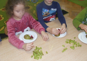 Dziewczynka i chłopiec robia jezyka z winogron.