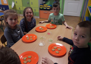 Dzieci siedzą przy stoliku, na którym stoją talerze z pierniczkiami