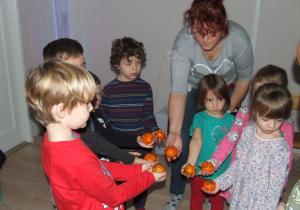 Dzieci pokazują świąteczne ozdoby wykonane z mandarynek.