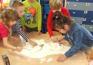 Dzieci mieszają mąkę i sodę.