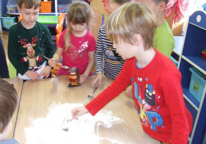 Dzieci mieszają mąkę i sodę.
