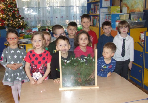 Grupa dzieci prezentuje wykonany las za szkłem.