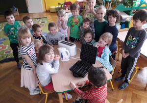 Dzieci oglądają czajnik elektryczny, toster i opiekacz