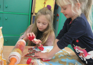 Dzieci wykrawają foremkami kształty ciasteczek.