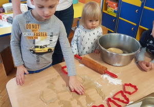Chłopiec wykrawa foremką ciasteczko.
