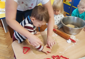 Chłopiec wykrawa foremką ciasteczko.