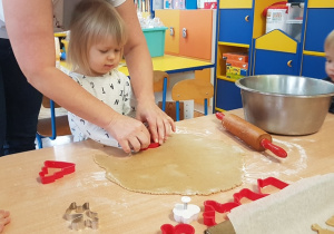 Dziewczynka wykrawa foremką ciasteczko.