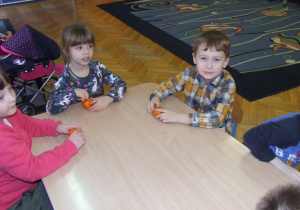 Dzieci dekorują mandarynki.