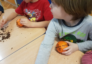 Dzieci ozdabiają pomarańczę.